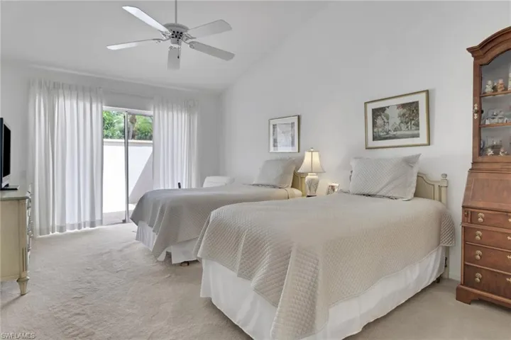 Bedroom featuring access to exterior, vaulted ceiling, light colored carpet, and ceiling fan