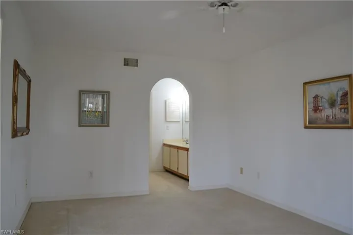 Spare room with ceiling fan, arched walkways, and light colored carpet