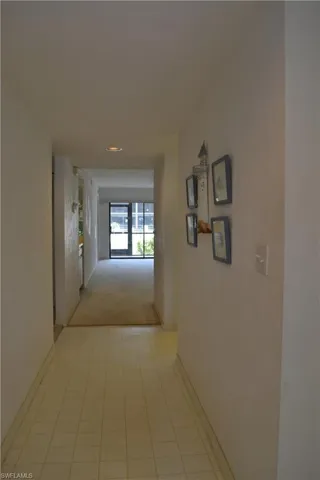 Corridor featuring light colored carpet and light tile patterned floors