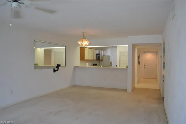 Unfurnished living room featuring light carpet and a ceiling fan
