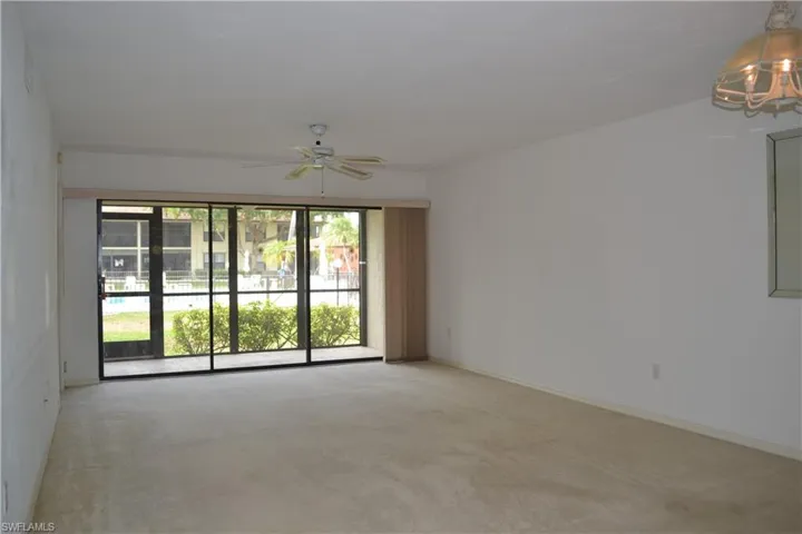 Empty room featuring light colored carpet, ceiling fan, and a chandelier