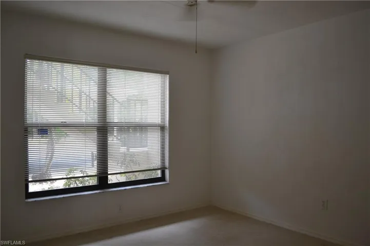 Carpeted spare room with ceiling fan and baseboards