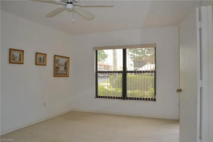 Carpeted empty room featuring a ceiling fan and baseboards