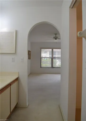 Corridor featuring arched walkways and light colored carpet