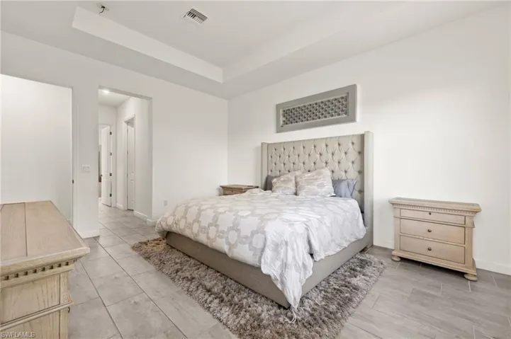 Tray ceiling, recessed lighting, tile flooring, white wall finishes, cased doorway
