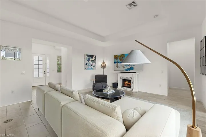 Recessed lighting, tray ceiling, fireplace with detailed mantel, and wood-finish flooring