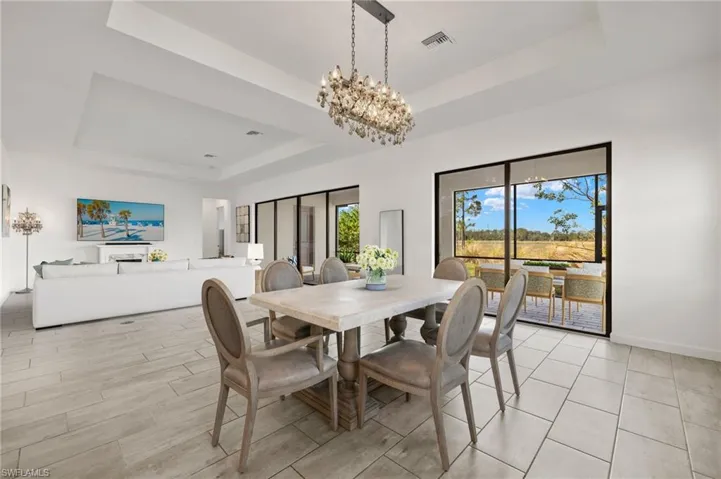Open-concept living space with tile flooring, tray ceiling, and sliding glass doors