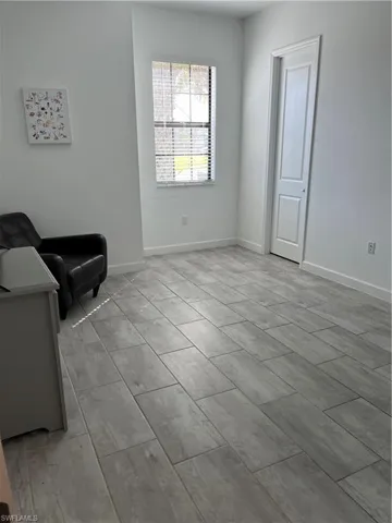 Rectangular tile flooring, a window with blinds, and white interior walls