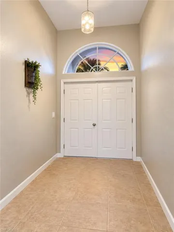 Double entry doors with an arched transom window, tiled flooring, and a pendant light fixture