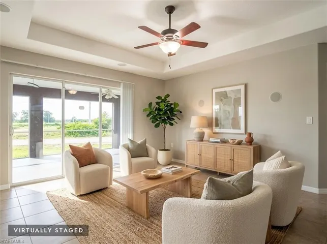 Tray ceiling with a ceiling fan light fixture, tile flooring, and sliding glass doors to the exterior