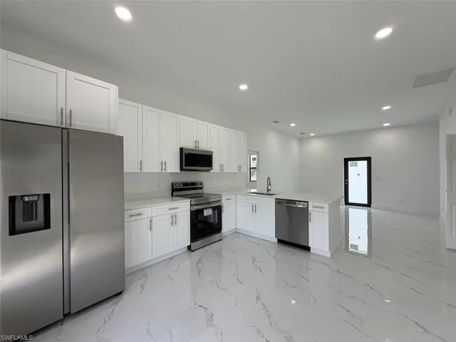 Contemporary kitchen with white cabinetry, stainless steel appliances, white countertops, and a full-height white subway tile backsplash