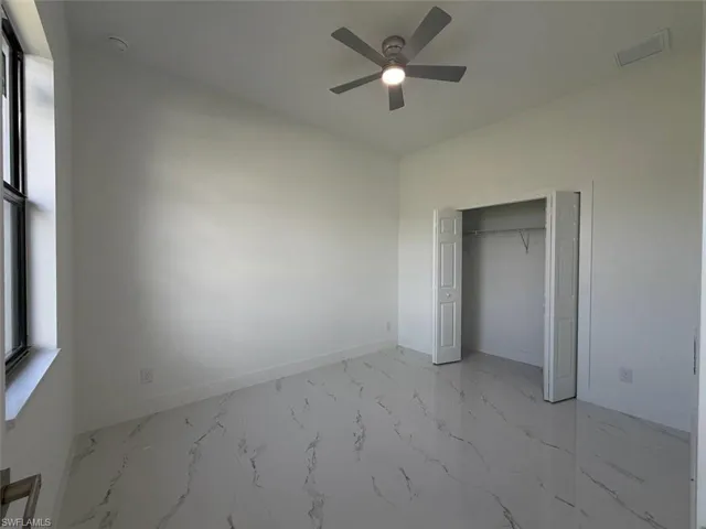 Recessed lighting, ceiling fan with integrated light, white walls, large window with dark trim, and a bi-fold closet