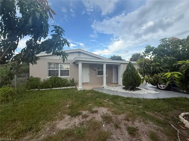 Ranch-style home with stucco siding, a porch, and a front lawn