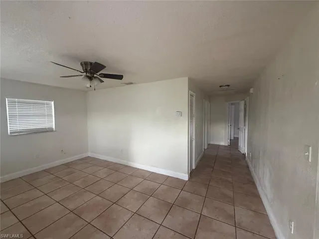 Unfurnished room with a textured ceiling, light tile patterned floors, and ceiling fan