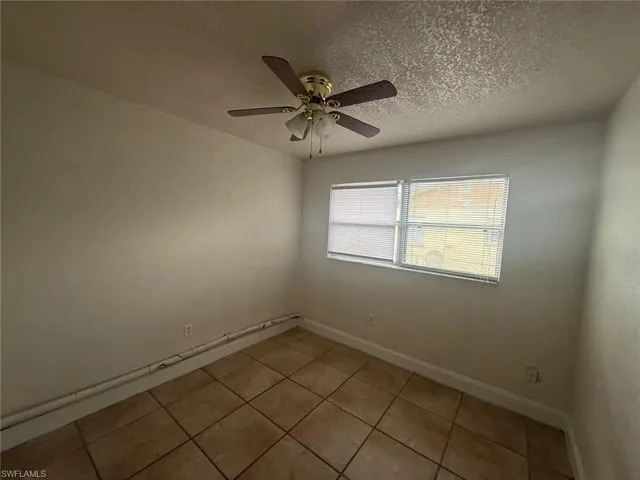 Spare room with a textured ceiling, light tile patterned floors, and a ceiling fan