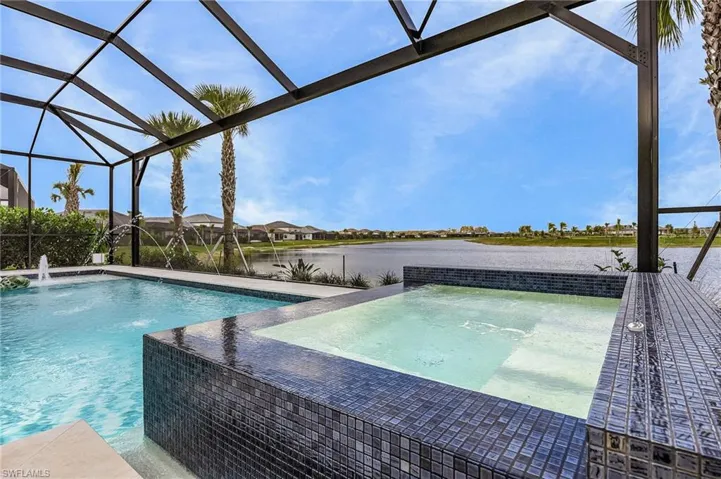 Swimming pool with a jacuzzi, glass enclosure, a sunroom, a patio area, and a residential view