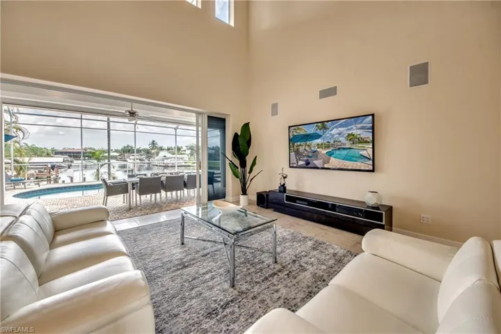 Tiled living room featuring a sunroom, a high ceiling, and a ceiling fan