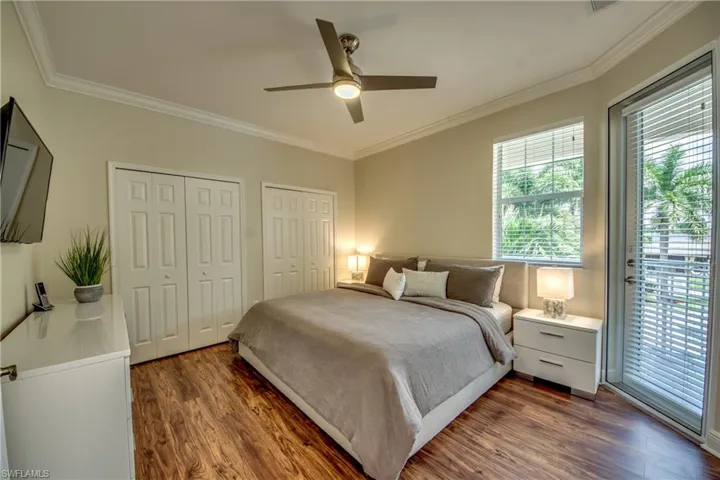 Bedroom with multiple closets, access to exterior, ornamental molding, ceiling fan, and dark wood-style floors