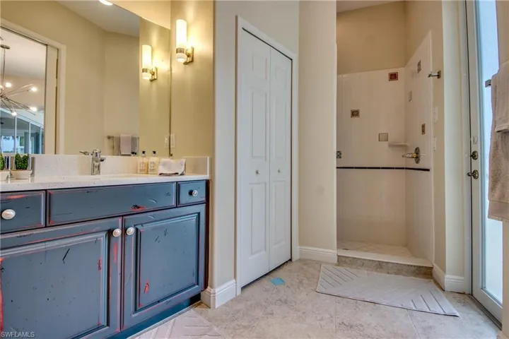 Bathroom featuring vanity, a closet, a walk in shower, and light tile patterned flooring