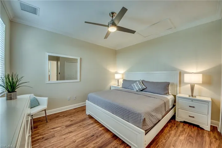 Bedroom with attic access, crown molding, wood finished floors, and a ceiling fan