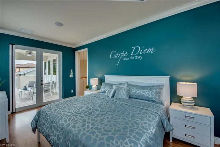 Bedroom featuring wood finished floors, access to exterior, and crown molding