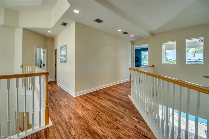 Hall with an upstairs landing, recessed lighting, and wood finished floors