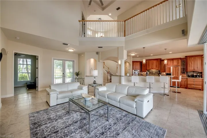 Living area featuring ceiling fan, arched walkways, recessed lighting, stairs, and a towering ceiling