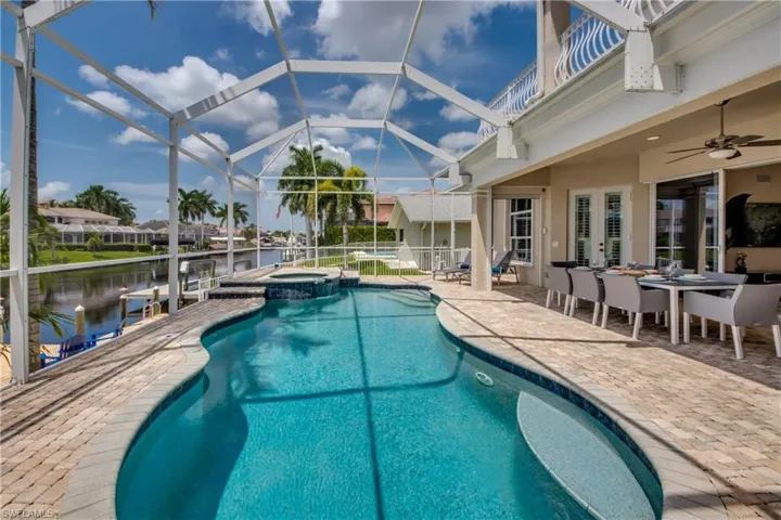 View of swimming pool featuring a sunroom, a patio, outdoor dining space, and glass enclosure
