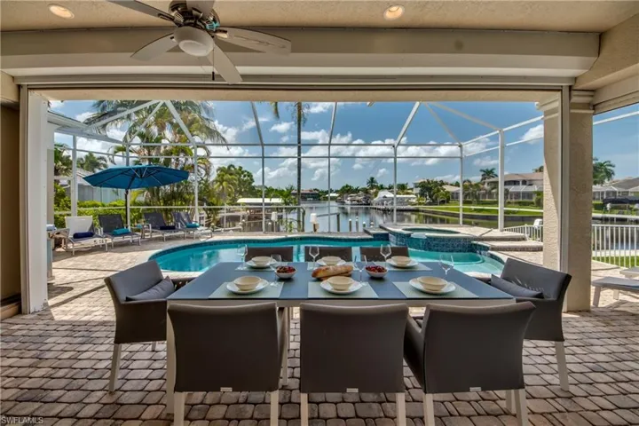 View of swimming pool with a sunroom, a patio area, outdoor dining area, a lanai, and a water view