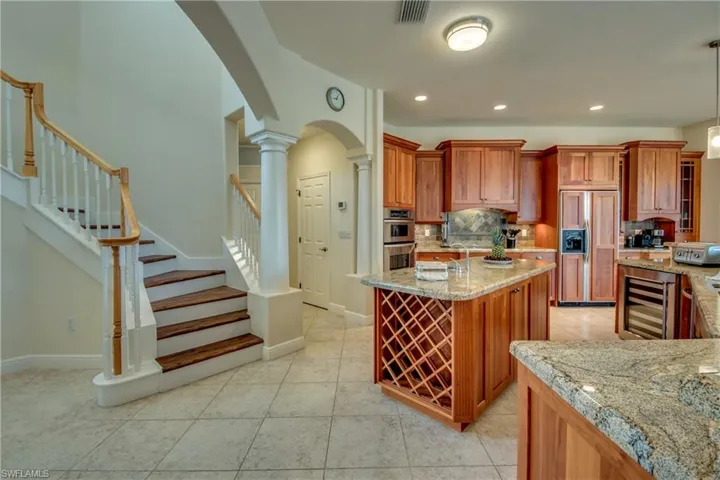 Kitchen featuring paneled fridge, beverage cooler, brown cabinets, arched walkways, and decorative backsplash