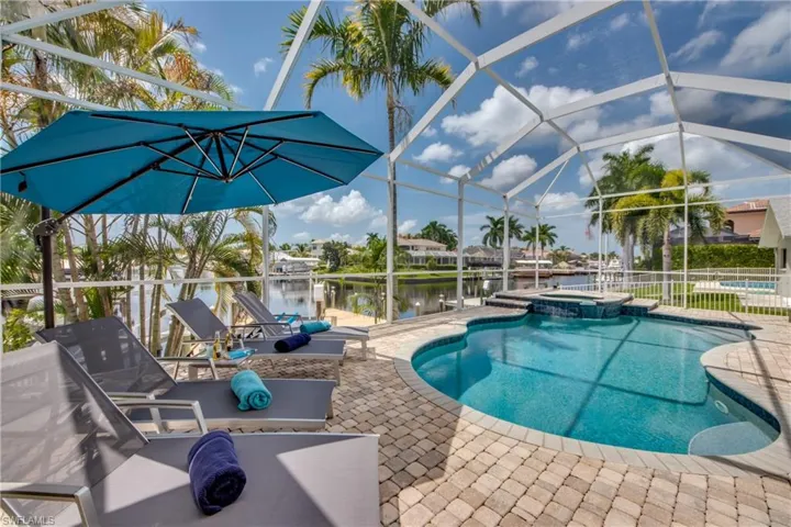 View of pool with glass enclosure, a patio, a water view, a pool with connected hot tub, and a sunroom