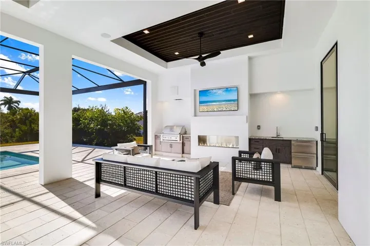 View of patio featuring an outdoor kitchen and area to lounge, a sunroom, a ceiling fan, a lanai, and an outdoor pool
