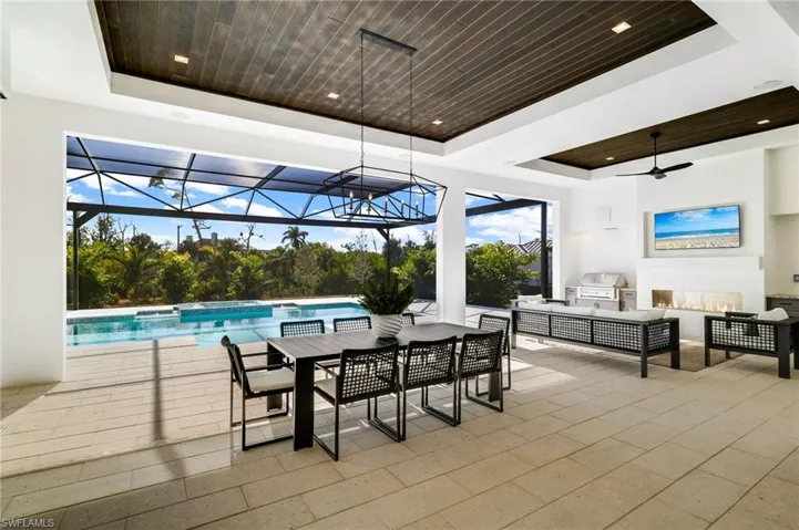 View of patio / terrace with area for grilling, a ceiling fan, a sunroom, a pool with connected hot tub, and outdoor lounge area