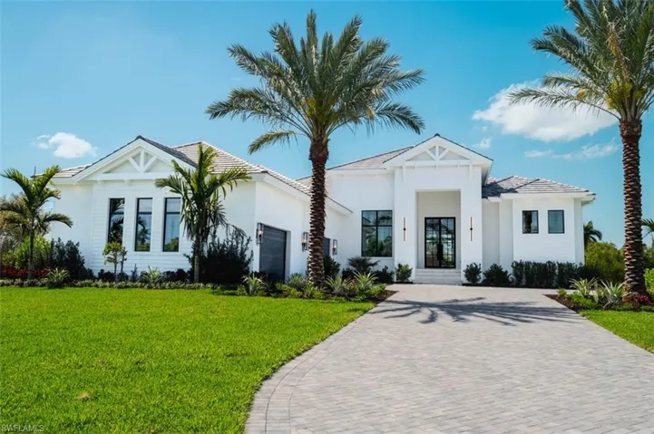 Modern farmhouse featuring decorative driveway, a front yard, stucco siding, and an attached garage