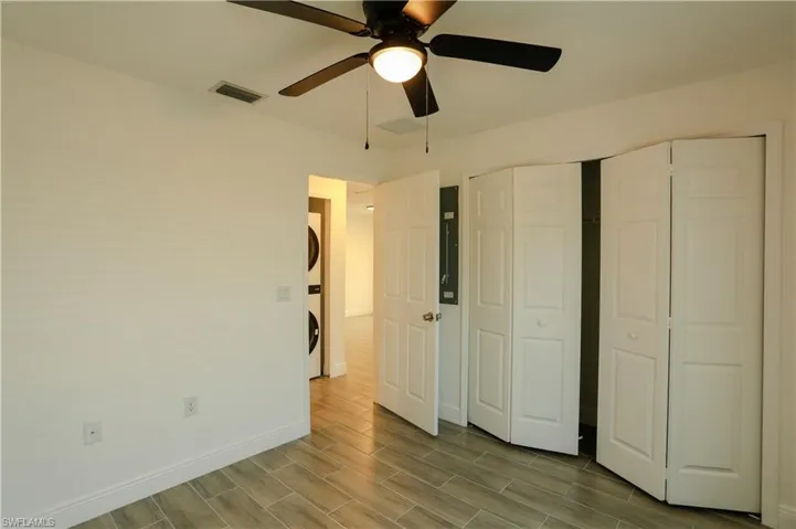 Interior room featuring light-toned walls, a black ceiling fan, and light wood-look tile flooring