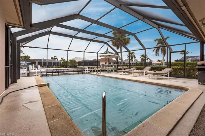 View of pool with glass enclosure and a patio area