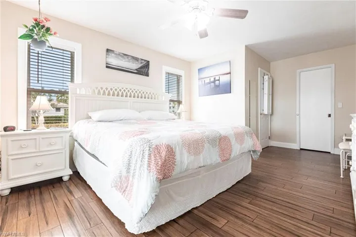 Bedroom with ceiling fan, dark wood-type flooring, and multiple windows