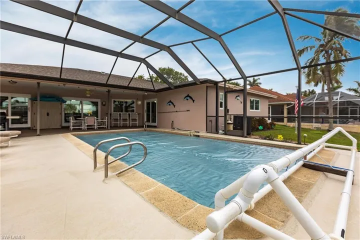 View of pool featuring a patio, glass enclosure, and exterior bar