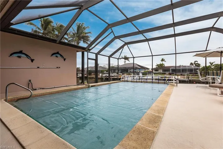 View of swimming pool with glass enclosure and a patio area