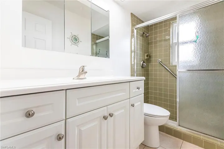 Bathroom featuring vanity, a shower with shower door, tile patterned floors, and toilet
