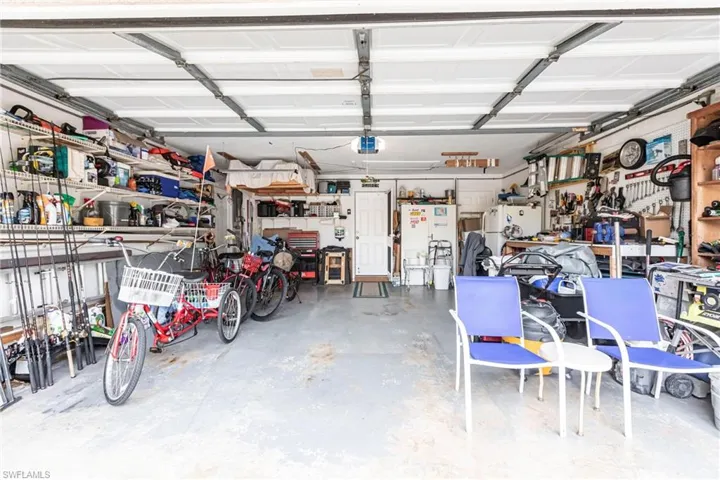 Garage with a workshop area, white fridge, and a garage door opener