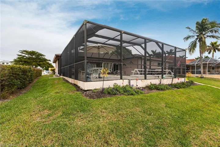 Rear view of house featuring a lawn, a lanai, and a patio area