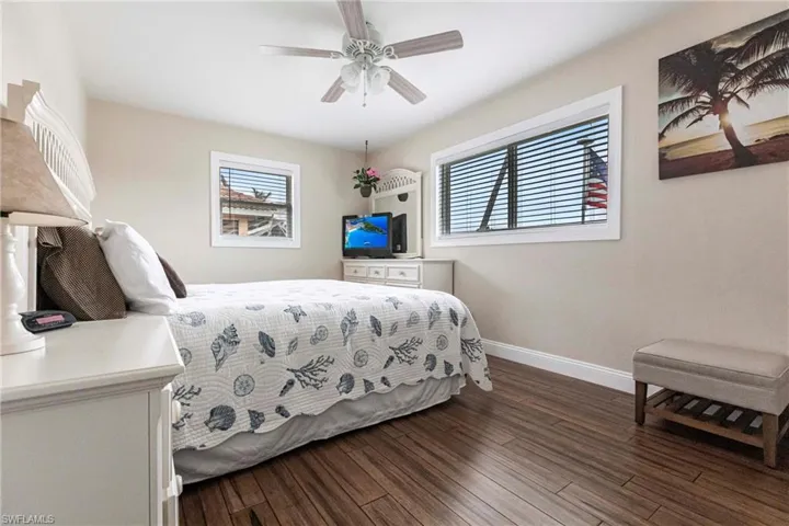 Bedroom with ceiling fan, multiple windows, and dark hardwood / wood-style flooring