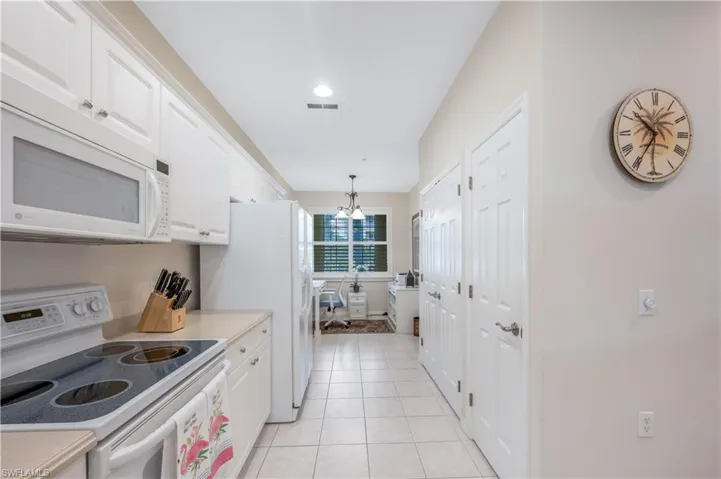 Kitchen featuring light countertops, white appliances, white cabinets, and light tile patterned flooring