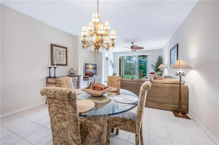 Dining area featuring light tile patterned floors, baseboards, and ceiling fan with notable chandelier
