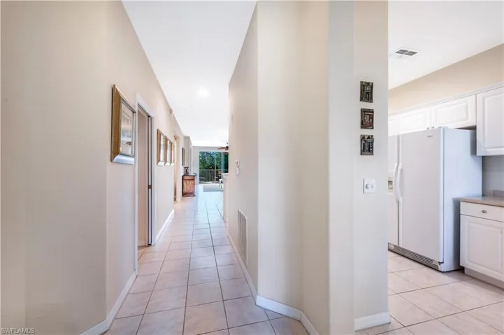 Corridor with light tile patterned flooring, visible vents, and baseboards
