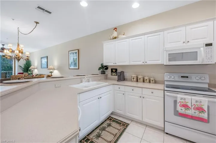 Kitchen with light countertops, white appliances, visible vents, and a sink