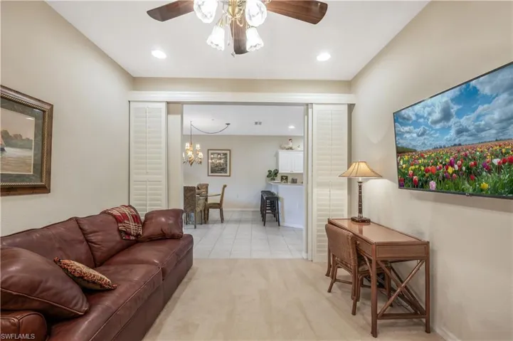 Living room with ceiling fan with notable chandelier, light tile patterned floors, baseboards, and recessed lighting