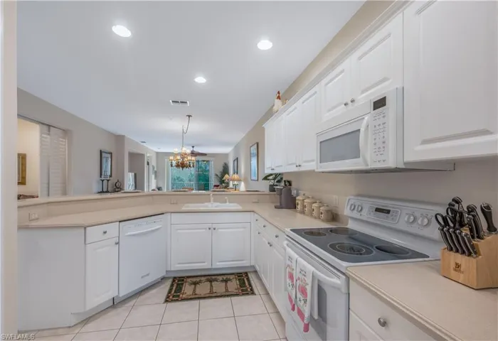 Kitchen with visible vents, an inviting chandelier, a sink, white appliances, and a peninsula