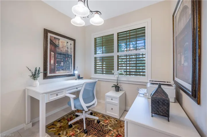 Office area with light tile patterned flooring, a notable chandelier, and baseboards